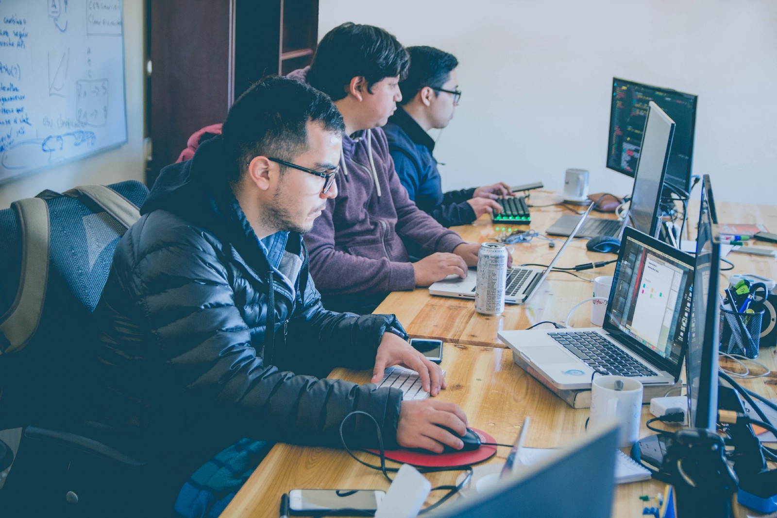 three men facing computer monitors” by Alvaro Reyes on Unsplash